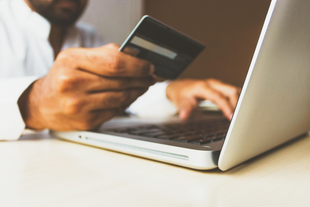credit card details being entered in website found by expert seo Blur man holding credit card in front of laptop signifying that good SEO leads to people spending money in your business